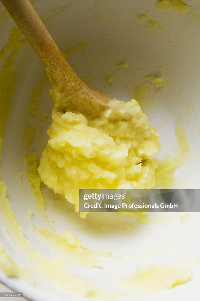 Remains of mashed potato on wooden spoon in bowl