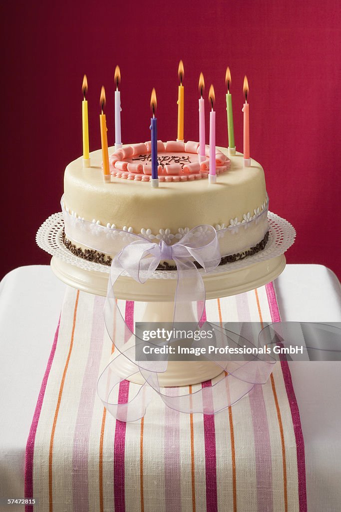 Birthday cake with burning candles on cake stand
