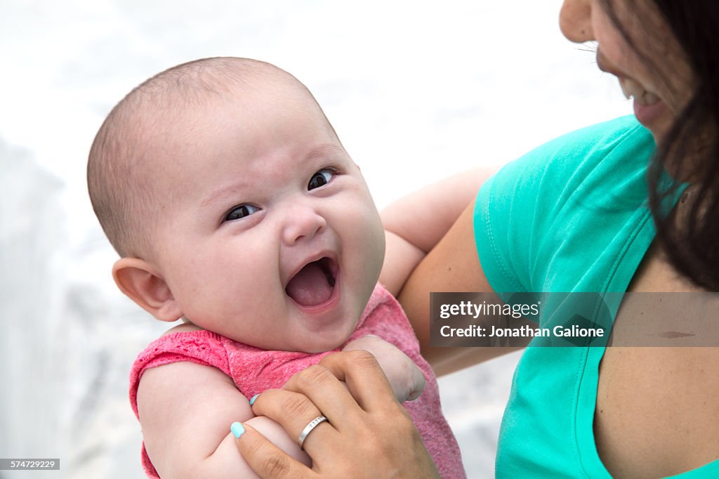 Smiling baby being held by its mother