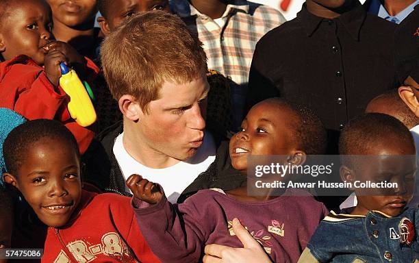 Prince Harry makes faces at children Mutsu and Lintle , in the grounds of the Mants'ase children's home while on a return visit to Lesotho on April...