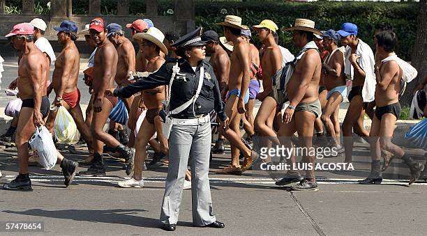Mexican policewoman directs the traffic during a march of stripped peasants, during a protest by members of the indigenous group "400 Pueblos", at...