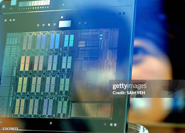 Woman watches a mask -a part used in wafer conception- at a show room of the 12-inch United Microelectronics Corp factory in Tainan, southern Taiwan,...