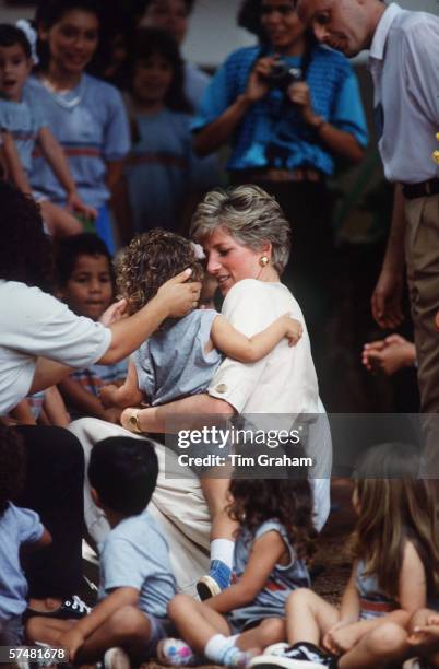 Princess Diana, Princess of Wales is seen cuddling a child and surrounded by children during a visit to a school on April 23, 1991 in Carajas,...