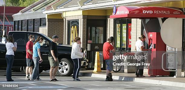 People stand in line to return and rent DVD's from a RedBox rental Machine at a McDonalds April 27, 2006 in Provo, Utah. The machines rent movies for...