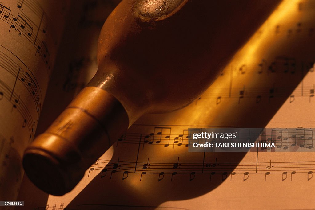 Wine bottle on musical notes, close-up, toned