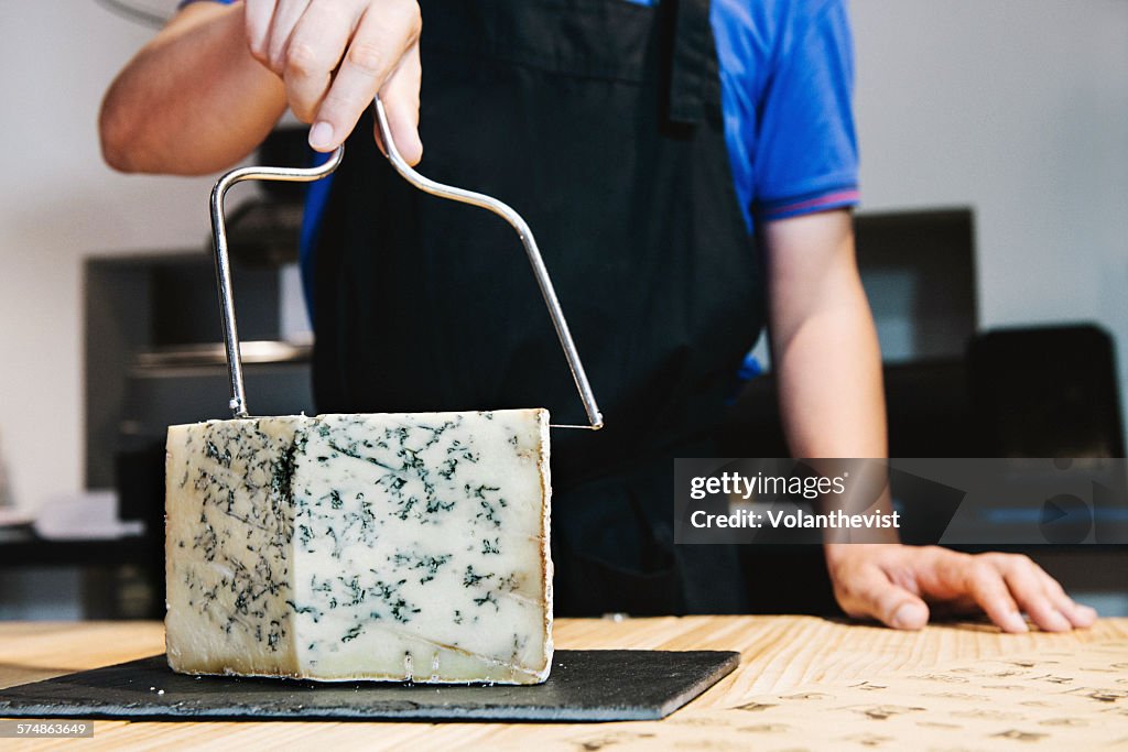 Man cutting gorgonzola in a in a cheese shop