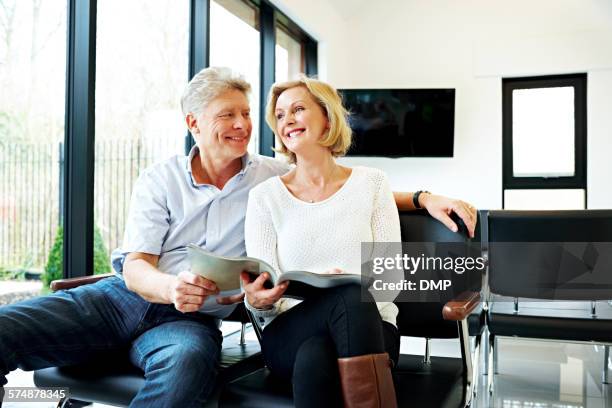 mature couple in waiting room smiling - treats magazine stock pictures, royalty-free photos & images