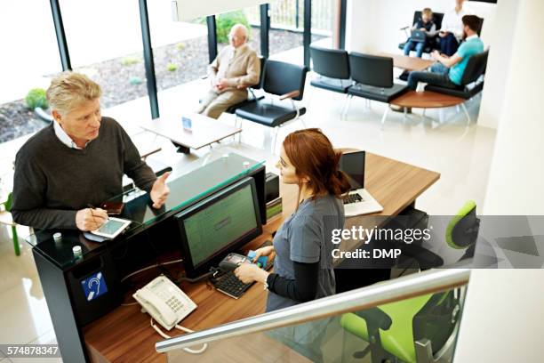 patient talking with receptionist at dental clinic - pre reception stockfoto's en -beelden