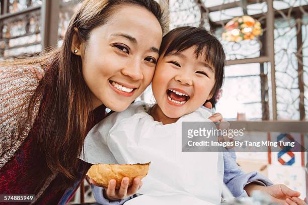 mom & daughter having meal joyfully in restaurant - familie hell weiss stock-fotos und bilder