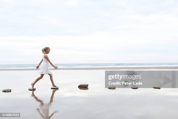 girl on stepping stones on beach - barefoot child stock pictures, royalty-free photos & images