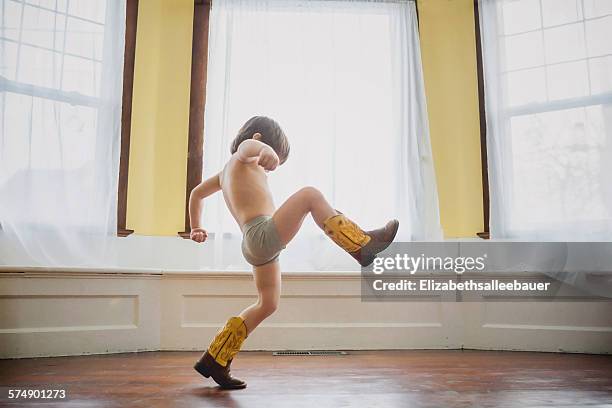 boy wearing stomping around indoors in cowboy boots - schreiten stock-fotos und bilder