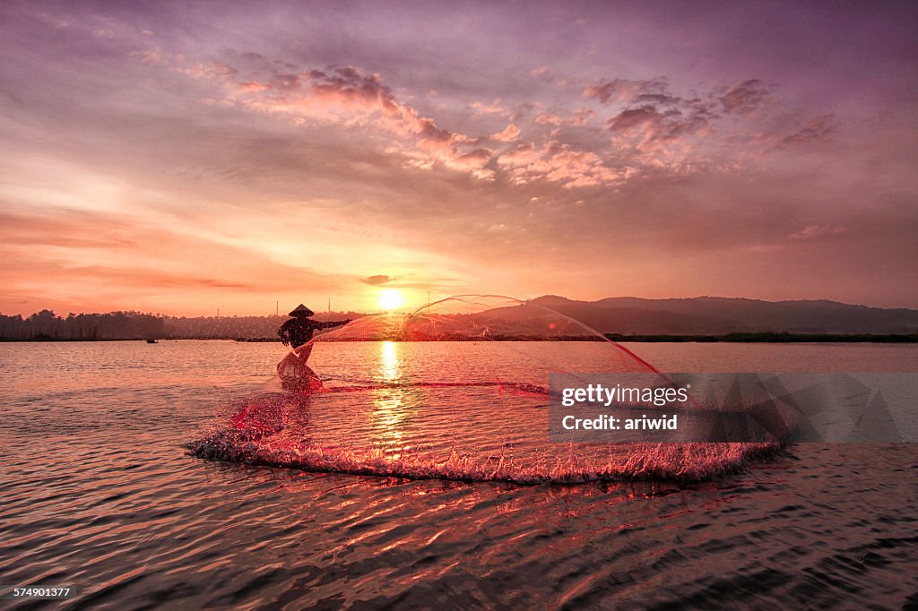 Silhouette of a fisherman catching fish at sunrise, Rawapening Lake, Java, Indonesia