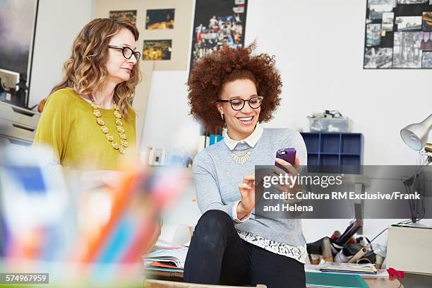 designer using smartphone in office - rm creatief stockfoto's en -beelden