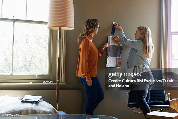 women discussing colour chart on wall - rm creatief stockfoto's en -beelden