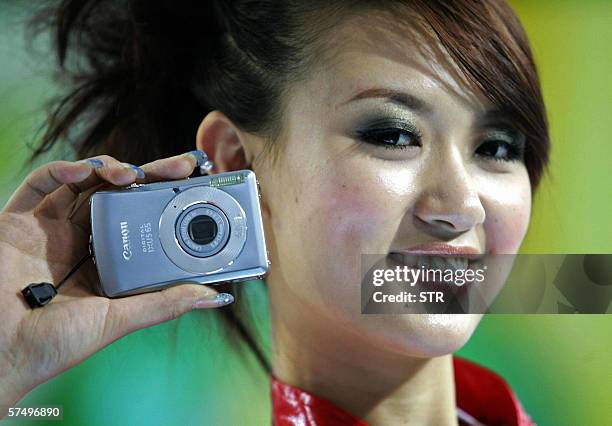 Chinese model shows off one of the latest mini digital camera from Japan's top maker of digital cameras Canon, at a digital fair in Beijing 30 April...