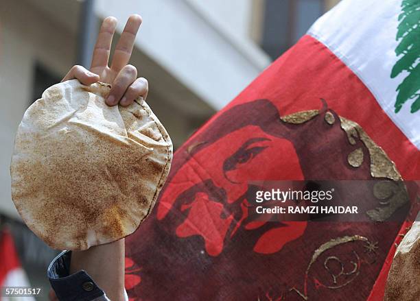 Lebanese hold up bread and their national flag decorated with a portrait of Argentine-born revolutionary leader Ernesto "Che" Guevara during a labour...