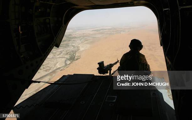 Inflight, AFGHANISTAN: A British machine-gunner mans his gun onboard a Chinook helicopter after taking off from Kandahar Airbase, 01 May 2006, for a...