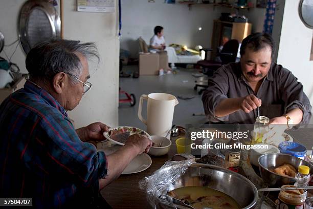 Inupiat Eskimos Tony Weyiouanna, right, and his father Steve enjoy a meal of frozen cod and dry cariboo meat dipped in seal oil, at Steve's house,...