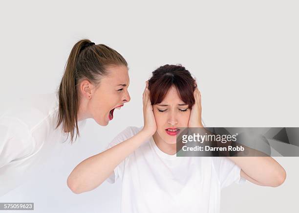 girl forcefully shouting at another girl - young man white tshirt stock-fotos und bilder