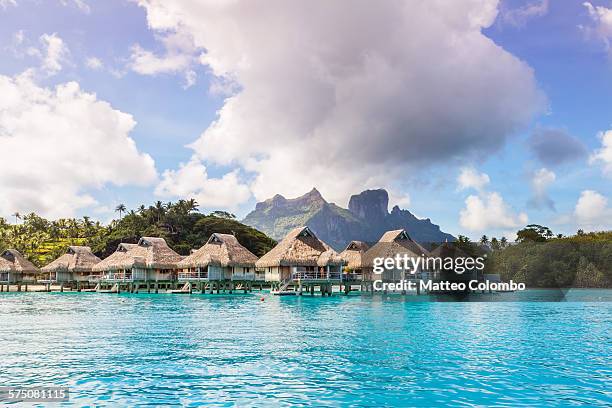 overwater bungalows in the lagoon of bora bora - strohgedeckte strandhütte stock-fotos und bilder