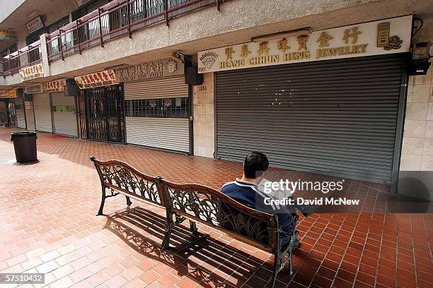 Man reads a newspaper in a courtyard of closed businesses in China Town several blocks from City Hall where a rally is about to begin on what is...