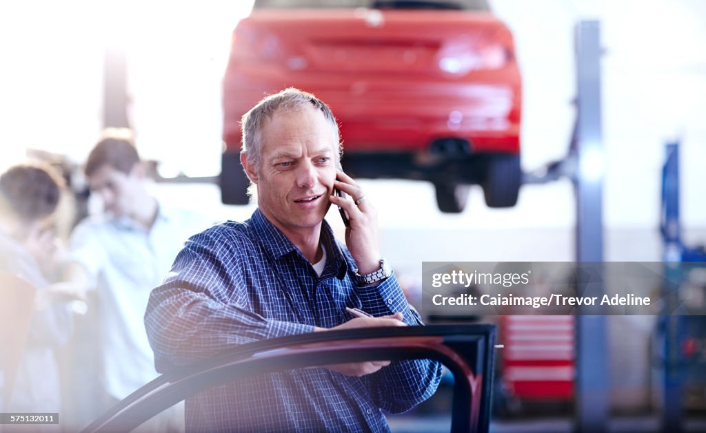 Man talking on cell phone in auto repair shop