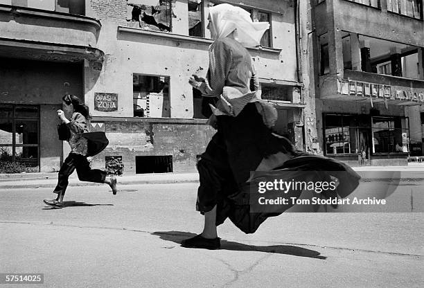 Women run across 'Sniper Alley' during heavy shooting in Sarajevo in 1993.