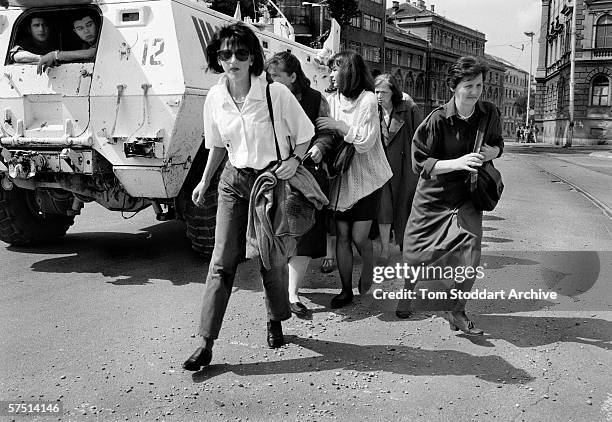 Women shelter behind a UN armoured personnel carrier as they cross 'Sniper Alley' during the siege of Sarajevo in 1995.