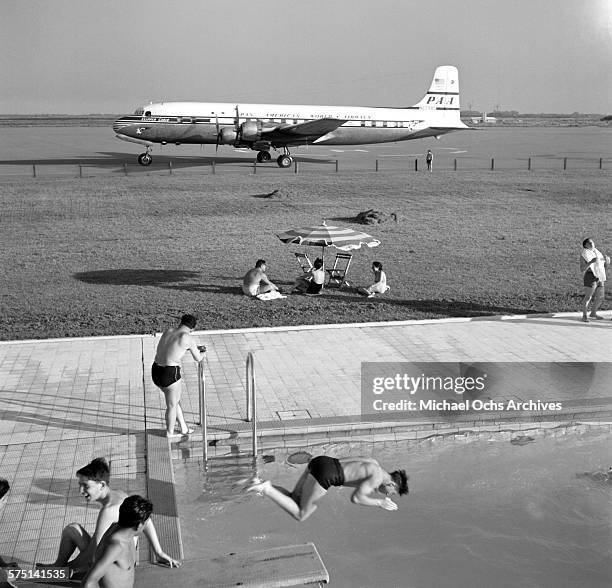 View of an Pan American Airways DC-4 Clipper airplane on the tarmac as people swim in a swimming pool at the Ezeiza Airport in Buenos Aires,...