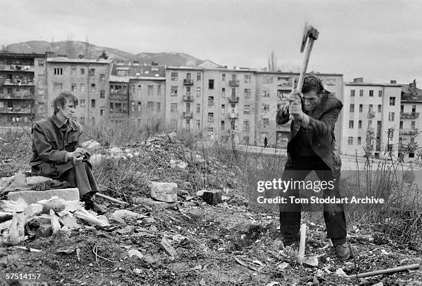 Desperate for wood to burn to keep warm, a Sarajevo couple chop up the roots of a felled tree in the winter of 1994.