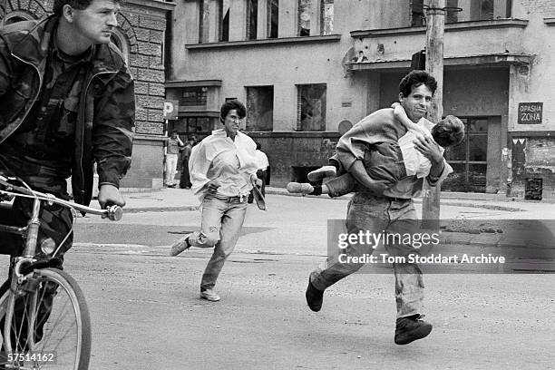 Family dash across 'Sniper Alley' to avoid gunfire during the siege of Sarajevo in 1994.