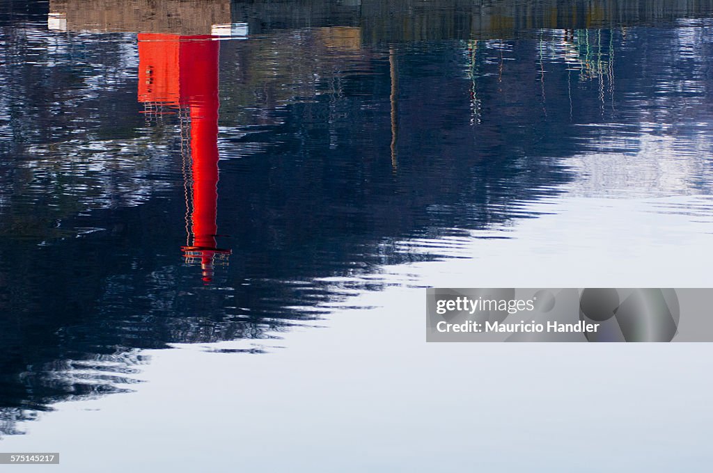 A red fishing port light reflection on a calm sea.