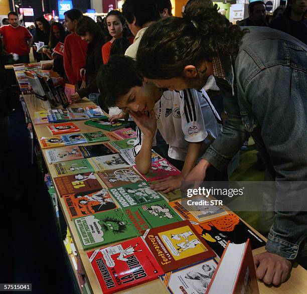 Buenos Aires, ARGENTINA: People watch books of Argentine writer and humorist Roberto Fontanarrosa while line up to get an autograph of the author at...
