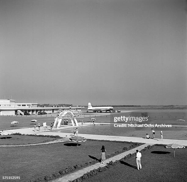 View of an Pan American Airways DC-4 Clipper airplane on the tarmac as people swim in a swimming pool at the Ezeiza Airport in Buenos Aires,...