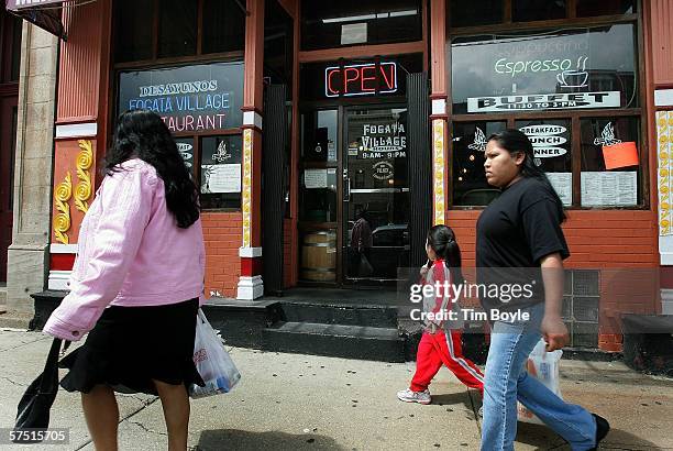 Pedestrians walk past the Fogata Village restaurant in Pilsen, a largely Hispanic neighborhood, on May 2, 2006 in Chicago, Illinois. The Fogata...