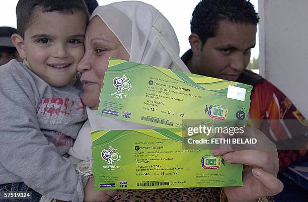 Tunisian woman holding her son shows 03 May 2006 her tickets for the first three matches of the 2006 Football World Cup in Germany. Tunisia is in...