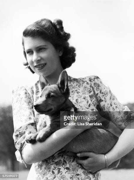 Princess Elizabeth holding Sue, a corgi pup, in the grounds of Windsor Castle, Berkshire, 30th May 1944.