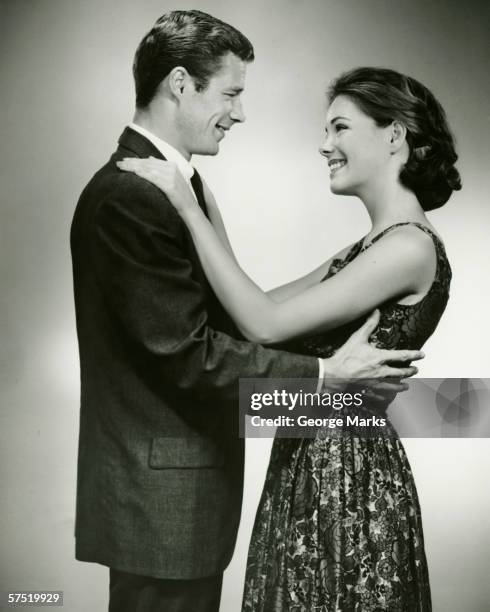 young couple standing face to face, smiling, in studio, (b&w) - 1950s couple stock pictures, royalty-free photos & images