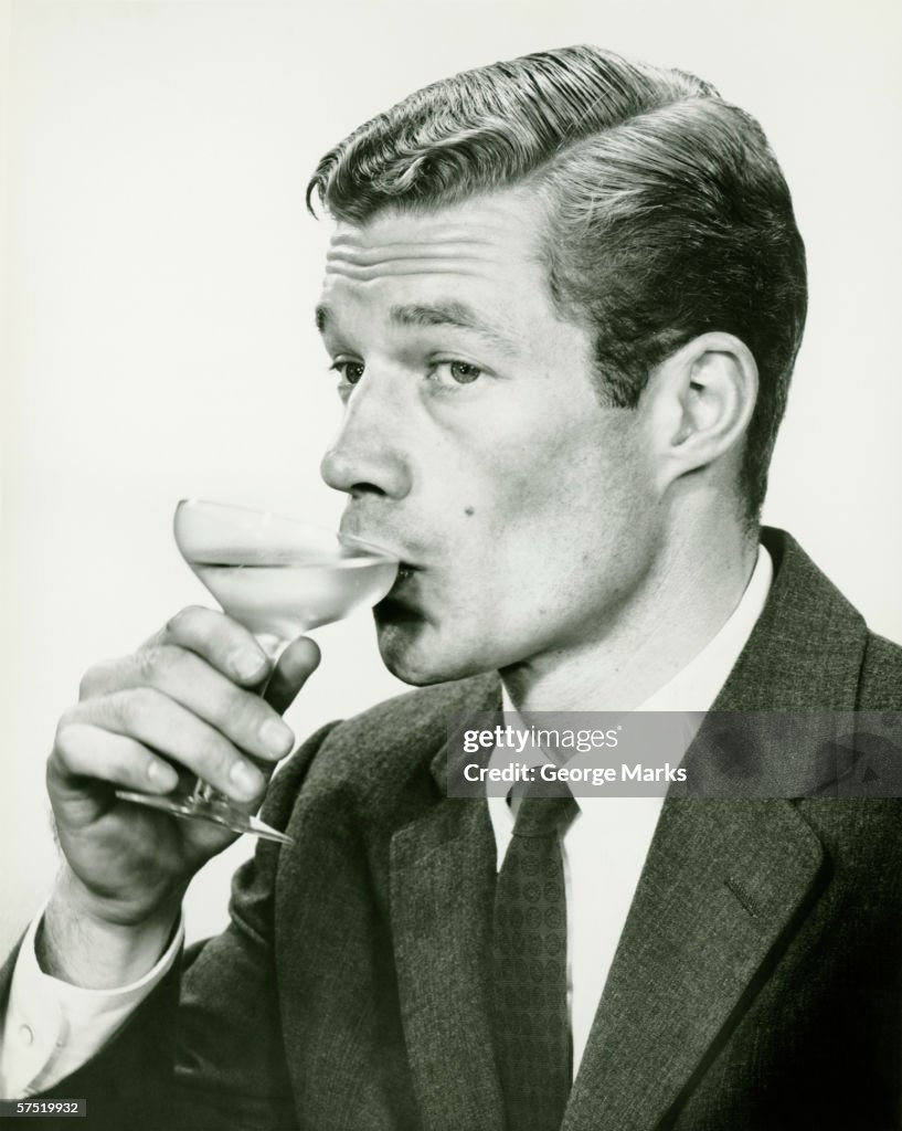 Young man in suit, drinking wine (B&W), portrait