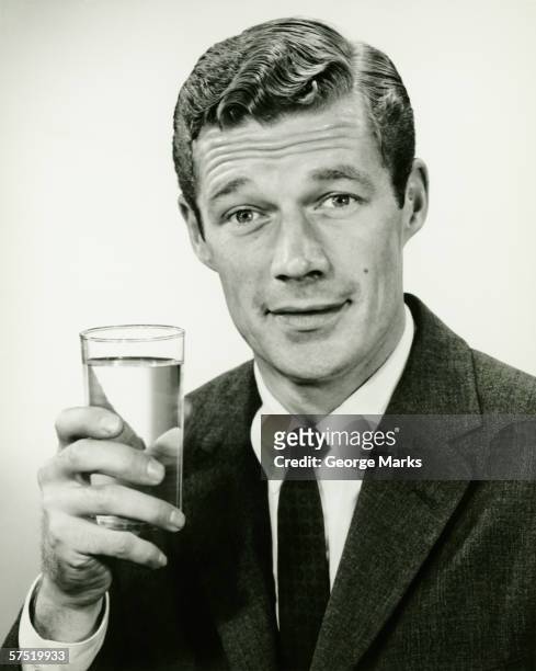 young businessman holding vaso de agua, posando en studio - george marks man fotografías e imágenes de stock
