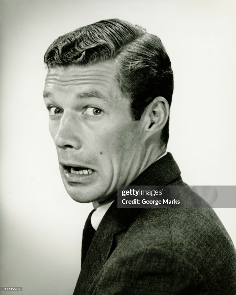 Young businessman looking frightened, posing in studio, (B&W), portrait