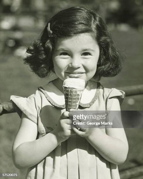 girl (3-4) holding ice cream, posing outdoors, (b&w), portrait - kinder 40er jahre stock-fotos und bilder