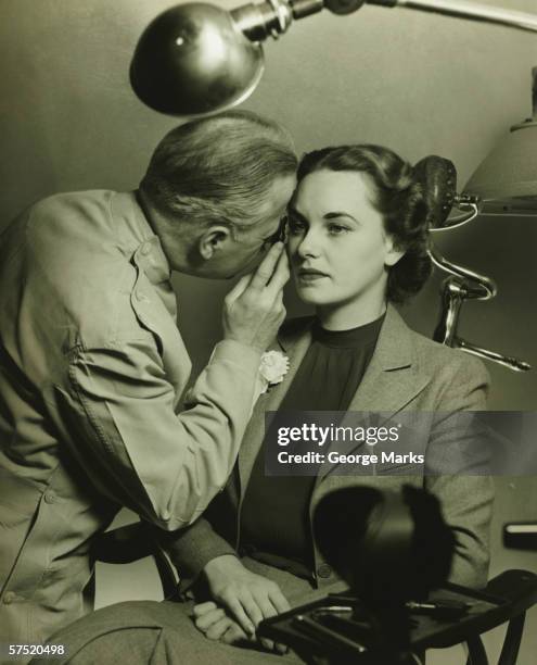 optician examining woman's eye, (b&w) - black and white doctor stock pictures, royalty-free photos & images