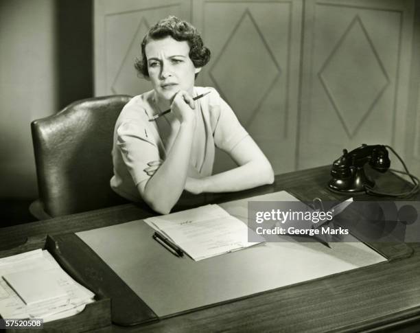 worrying woman sitting at desk in office, (b&w) - angry woman vintage stock pictures, royalty-free photos & images