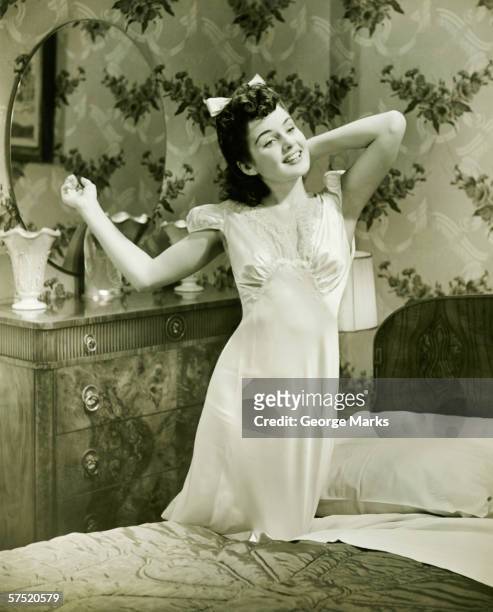 young woman in nightgown kneeling on bed, (b&w) - 1940s bedroom stock pictures, royalty-free photos & images