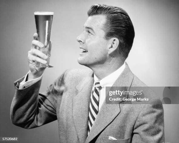 businessman in full suit in studio holding glass of beer, (b&w) - beer advertisement stock pictures, royalty-free photos & images