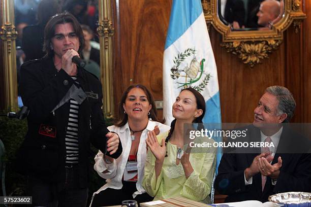 Colombian Juanes singns "Camisa Negra" as Gutemalan President Oscar Berger and US actress Asheley Judd clap, during a ceremony at the presidential...