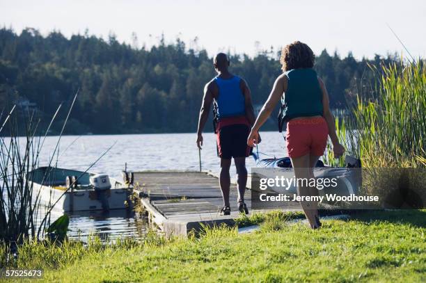 couple carrying canoe out to lake - ventil stockfoto's en -beelden