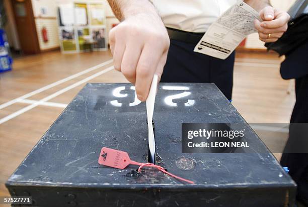 United Kingdom: A voter places his voting card into a ballot box at a polling station in Wandsworth, in south-London, 04 May 2006, during local...
