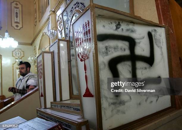 Jewish worshipper prays near a large Swastika that desecrates the Grand Synagogue May 4, 2006 in Petah Tikva in central Israel. Jewish worshippers...